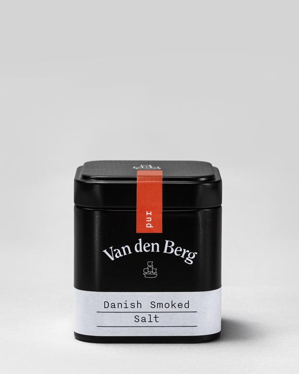 Eine schwarze Dose mit der Aufschrift „Van den Berg“ enthält dänisches Rauchsalz, das sich perfekt dazu eignet, beliebten Gerichten der deutschen Küche wie dem Schwäbischen Kartoffelsalat eine einzigartige Note zu verleihen. Das minimalistische Design mit einem roten Streifen auf dem Deckel vor einem sanften grauen Hintergrund macht die Dose zu einer eleganten Ergänzung für jede Küche.